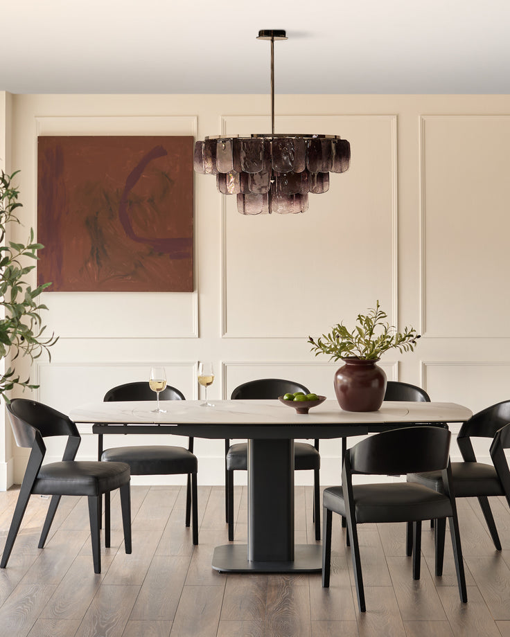 Fraser extending dining table in white ceramic with black base, seats six with black chairs in modern dining room.