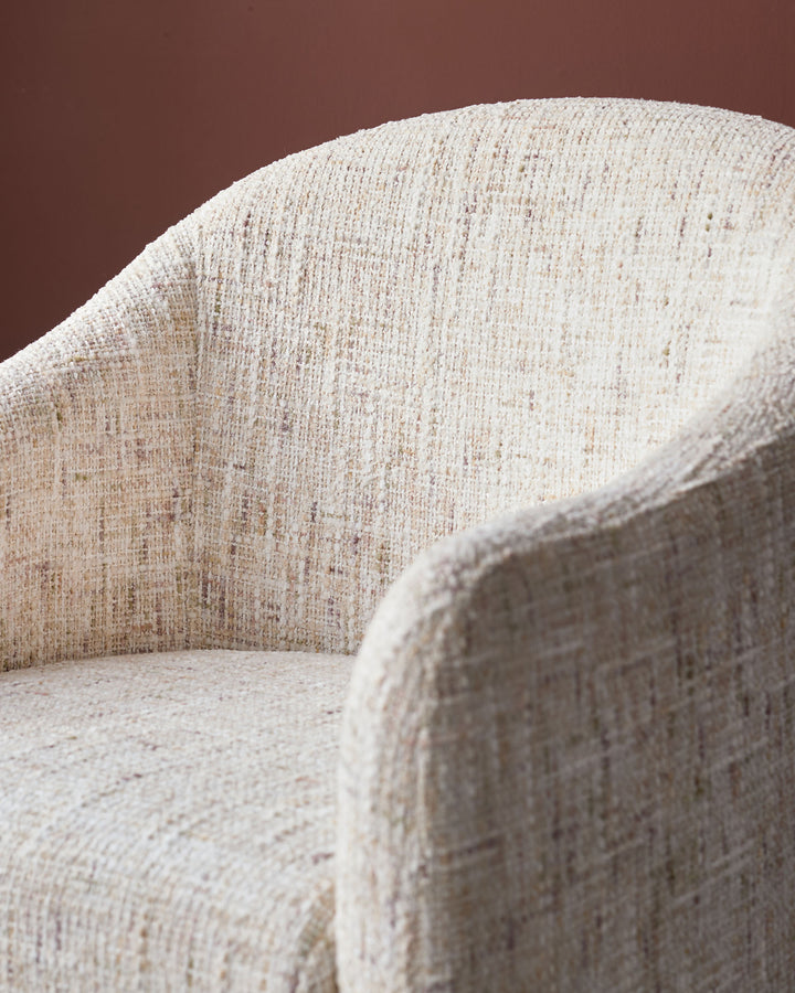 Freya dining chair in natural fabric, close-up detail showing curved backrest and woven texture.