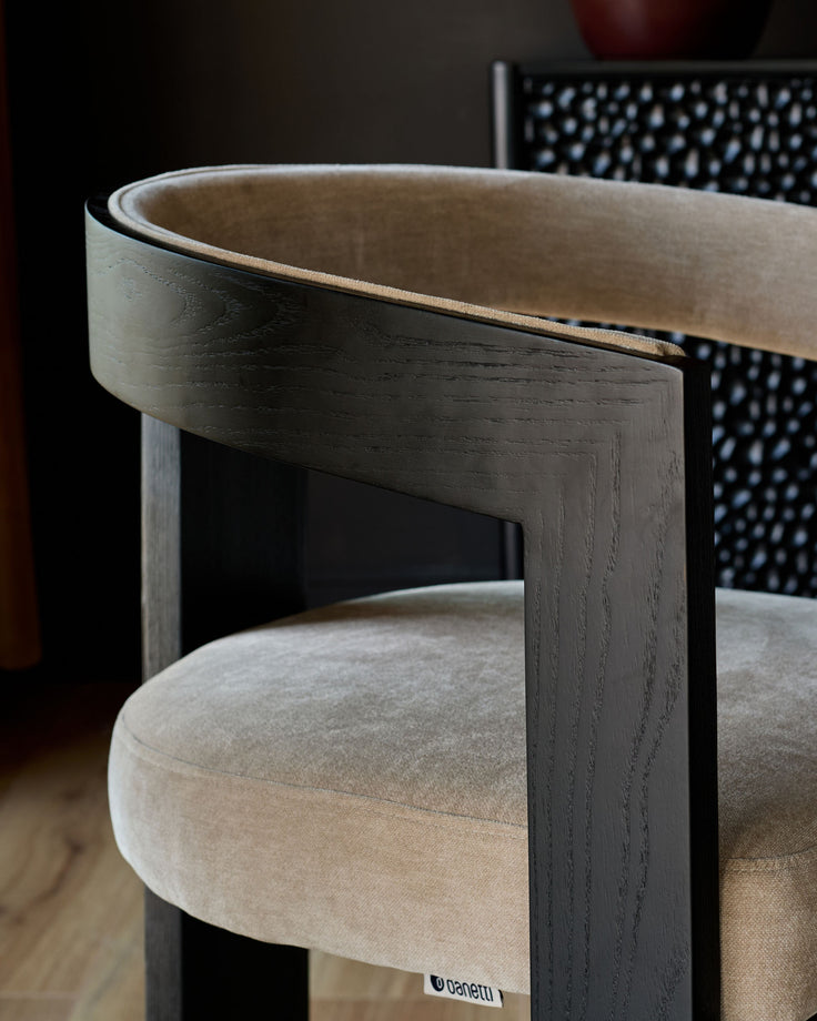 Garcia dining chair in champagne fabric with dark wood frame, shown at an angle highlighting the curved backrest and seat.