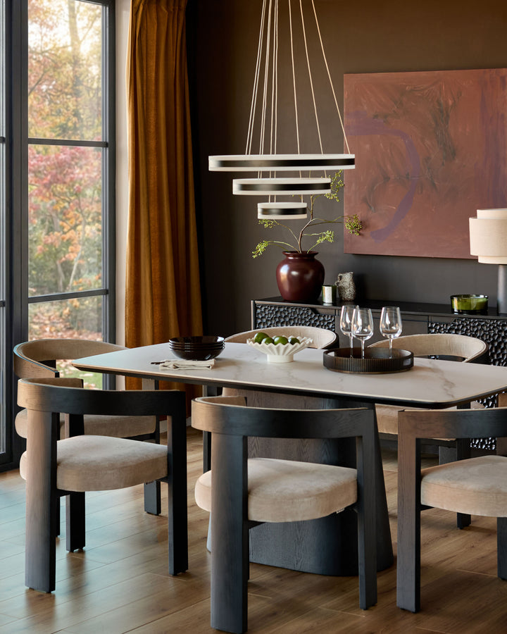 Garcia dining chair in champagne fabric with black wooden frame, shown at marble table in modern dining room.