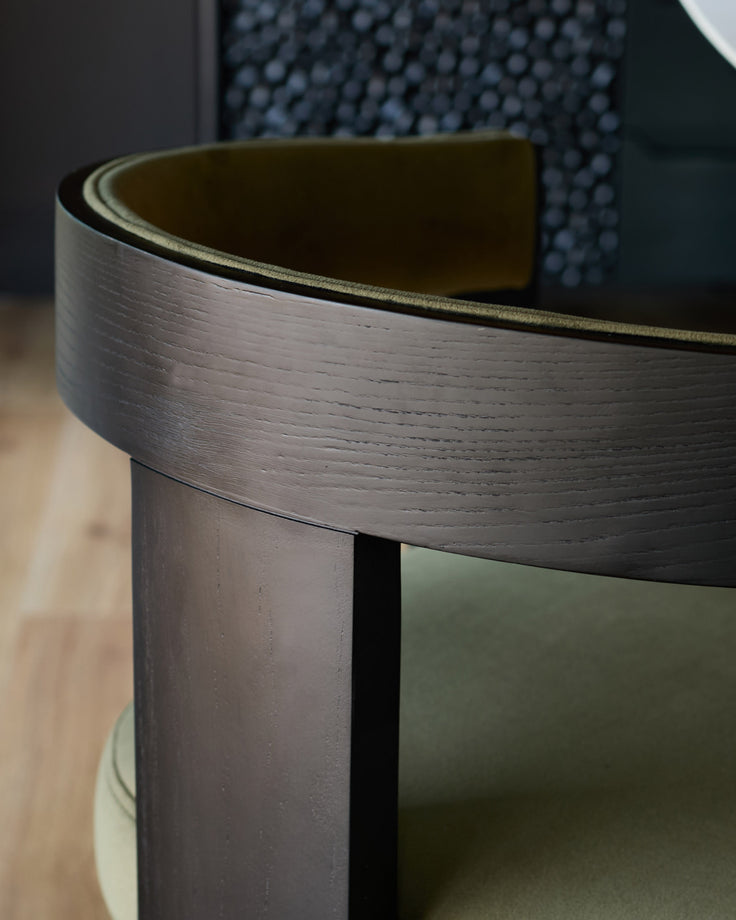 Dark wood curved backrest detail of Garcia dining chair with olive green velvet seat visible below.