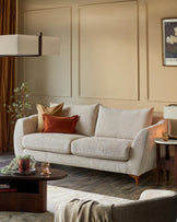 Genevieve 2-seater sofa in natural weave fabric with wooden legs, styled in a warm, neutral living room setting.