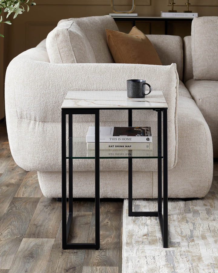 Side table with marble top, black frame, and glass shelf. Sofa and rug in the background.