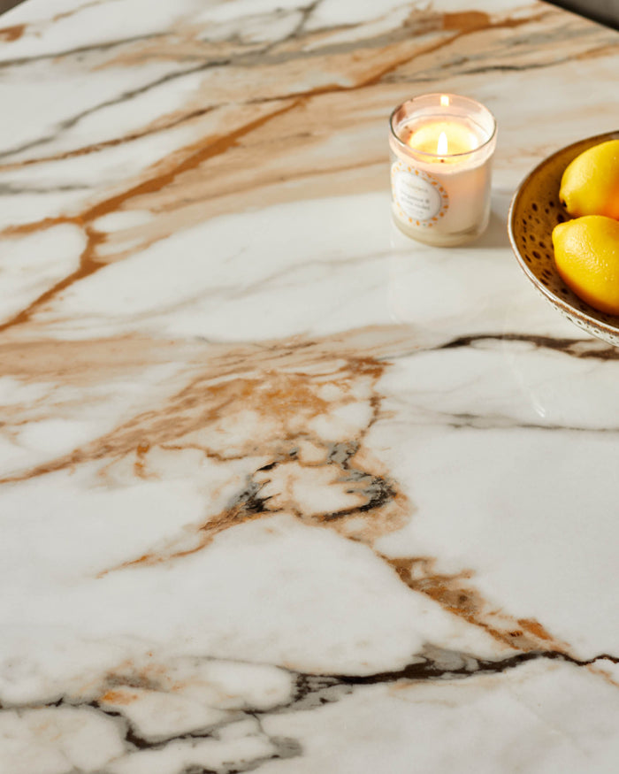 Close up of a marble table with a candle and lemons. Perfect for adding a touch of luxury to your home.