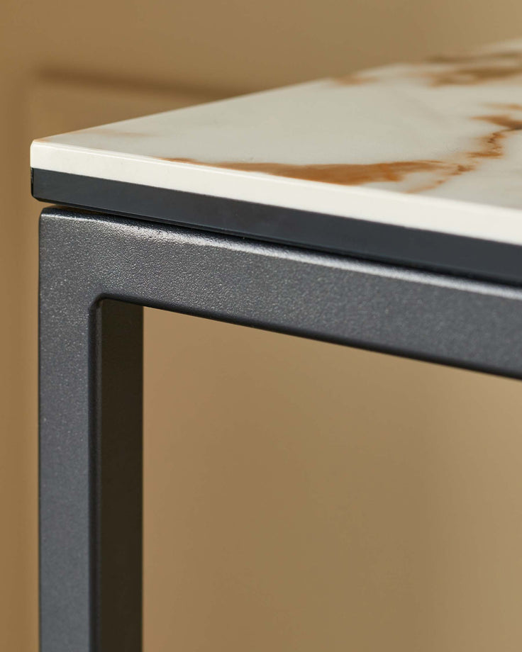 Close-up of a stylish side table with a faux marble top and sleek, dark metal frame. Ideal for modern living spaces.