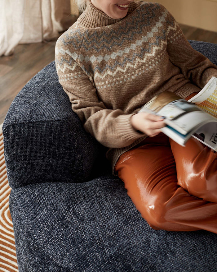 A plush, curved navy armchair provides a cosy space for relaxation, perfect for a modern living room.