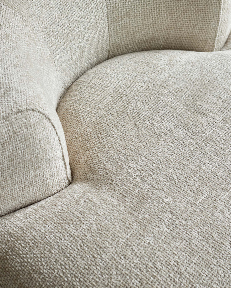 Close-up of a soft, textured beige upholstery on a rounded furniture piece, showcasing a cozy and modern design.