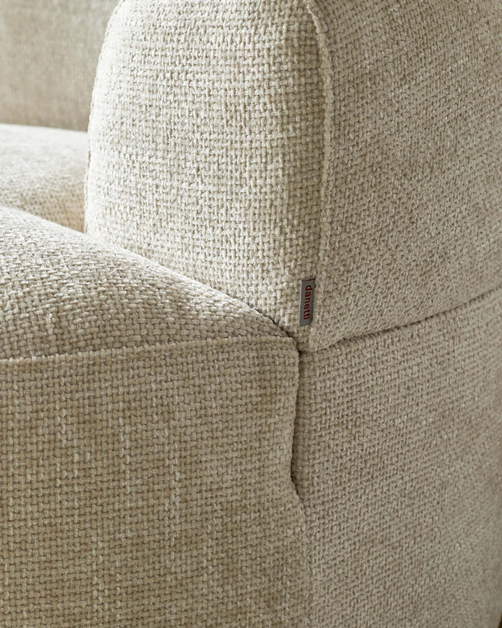 Cream textured upholstery of a contemporary sofa, featuring rounded edges and a subtle brand tag.