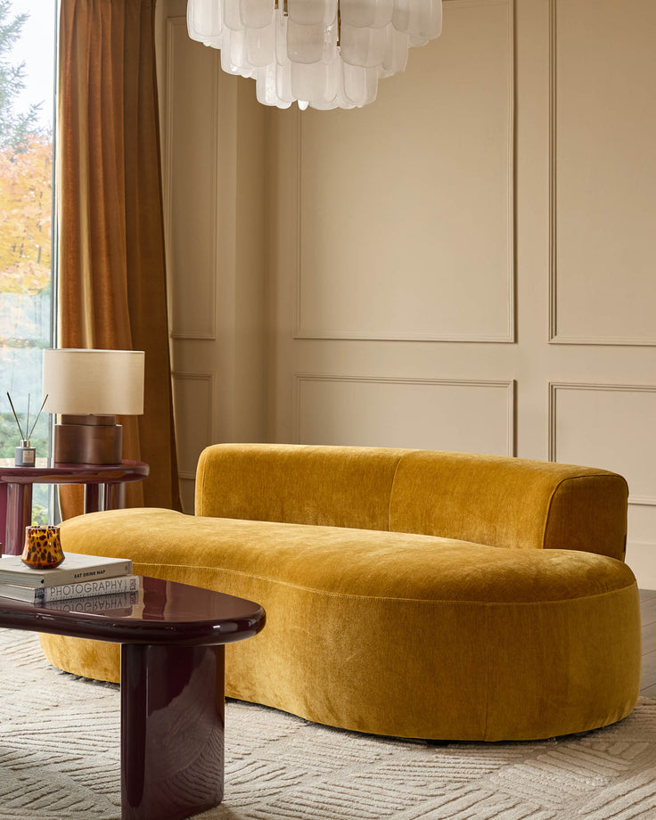 Gianna 2-seater sofa in ochre fabric with curved design, shown in styled living room setting.