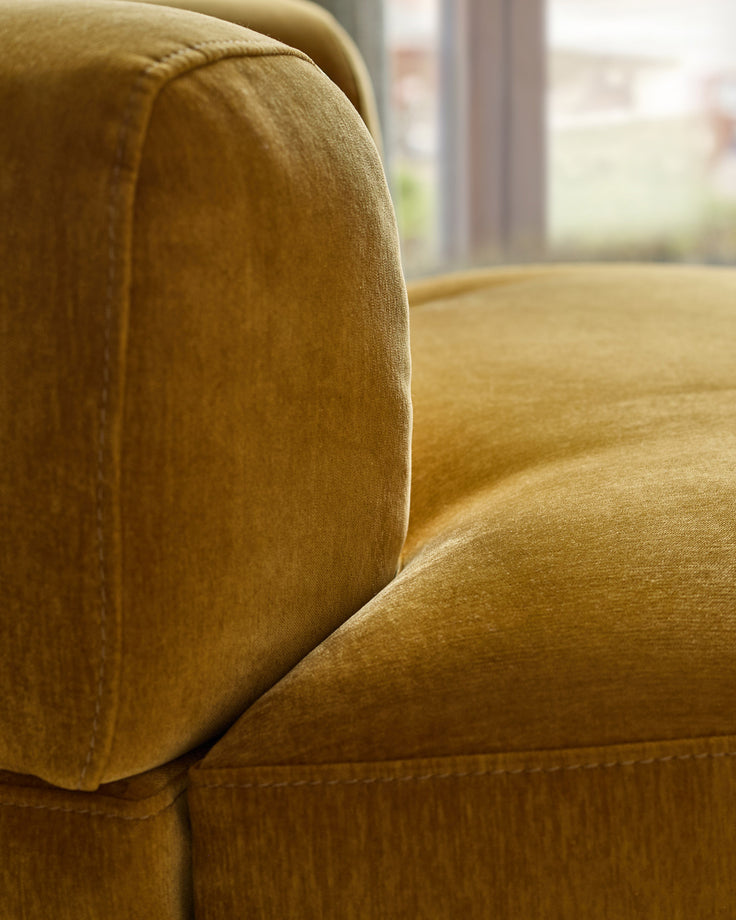 Gianna armchair in ochre fabric, close-up detail of padded armrest and seat cushion.