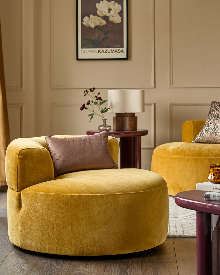 Gianna armchair in ochre fabric with curved design, shown in styled living room setting with accent pillow.