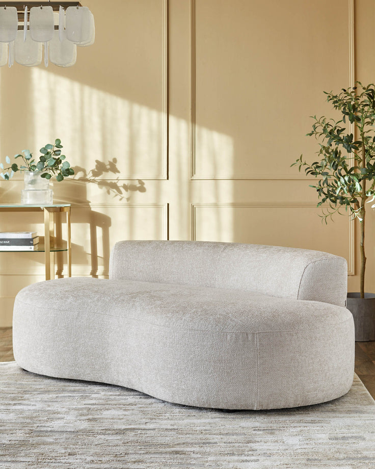 A curved, contemporary chaise lounge sits on a patterned rug, with a stylish side table and plant completing the scene.