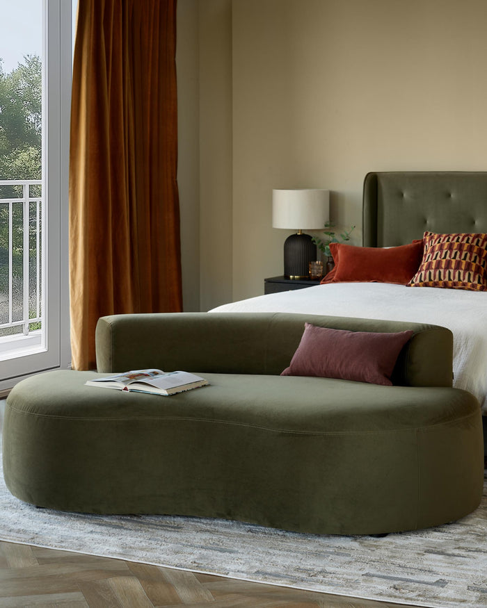 Stylish bedroom featuring a green velvet sofa and bed with olive headboard. A luxurious and inviting space.