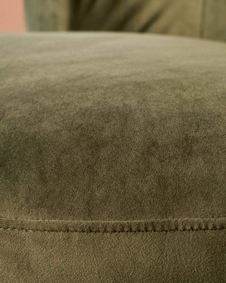 Close-up of an olive green upholstered cushion with a stitched seam. The soft material looks comfortable and inviting.