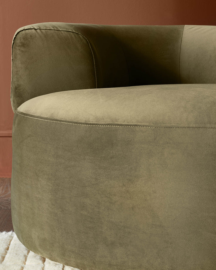 Close-up of a round, olive green velvet chair with a curved backrest. Stylish and comfortable seating for any living space.