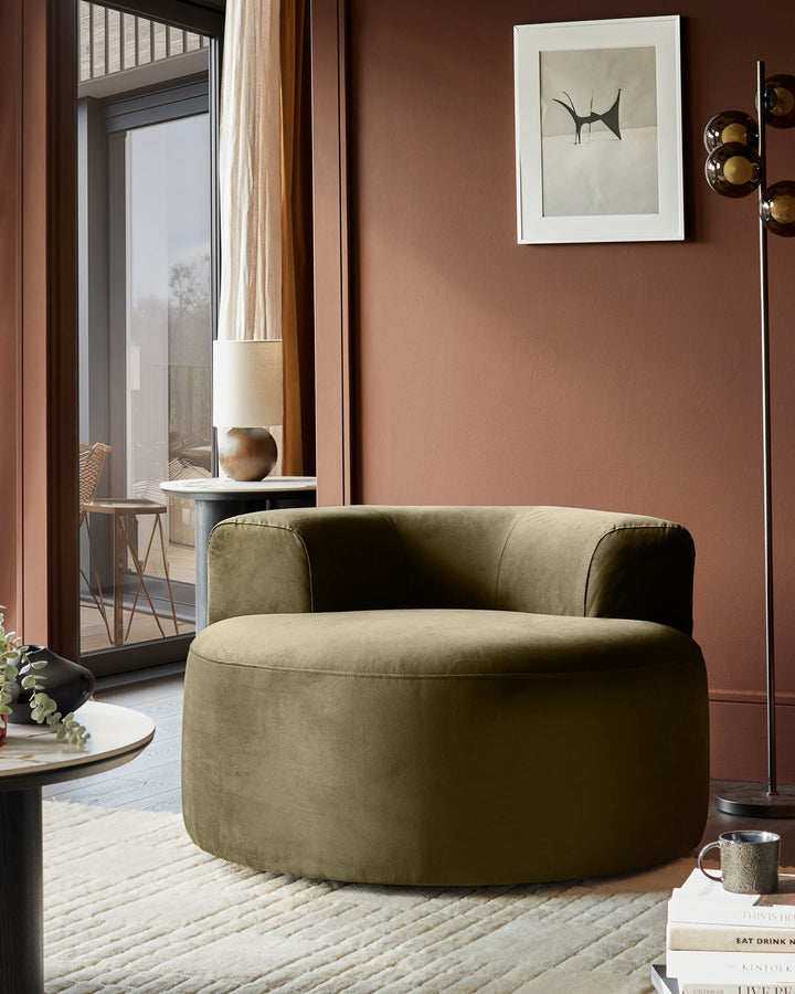 A cosy lounge, showcasing a plush, round armchair, alongside a small table and stylish floor lamp. Perfect for a relaxing living space.