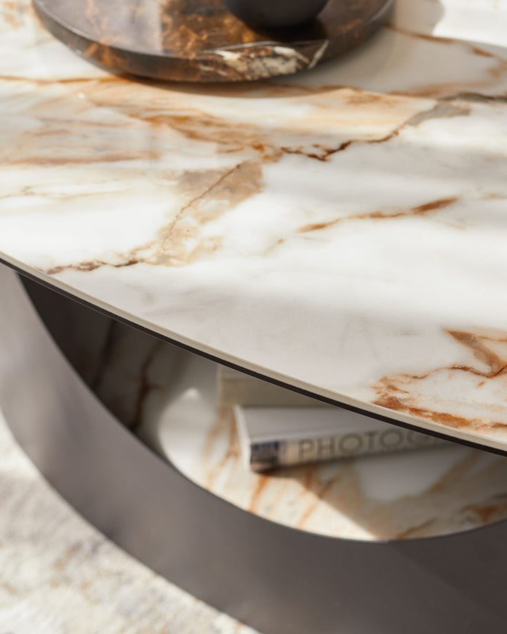 A stylish coffee table with a marble top and a modern metal base. Storage shelf underneath.