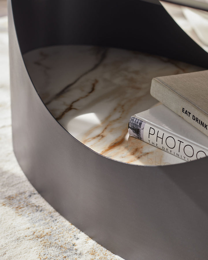 Stylish coffee table with a marble top and dark, curved metal frame. Features books titled 'Eat Drink' and 'Photo'.