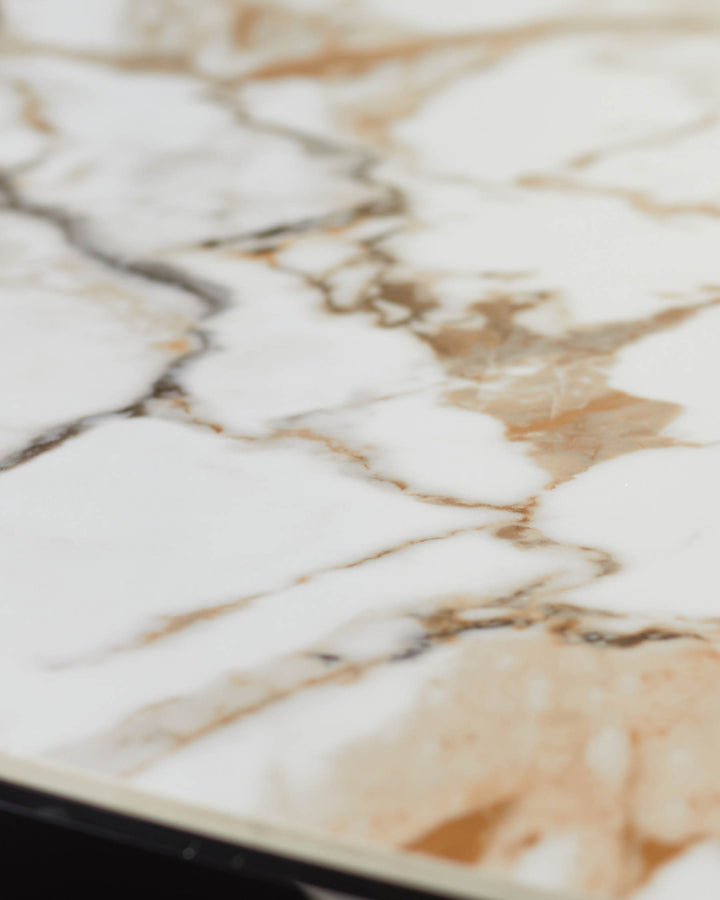 Close-up of a marble table top featuring delicate brown and grey veining, sitting on a sleek black frame.