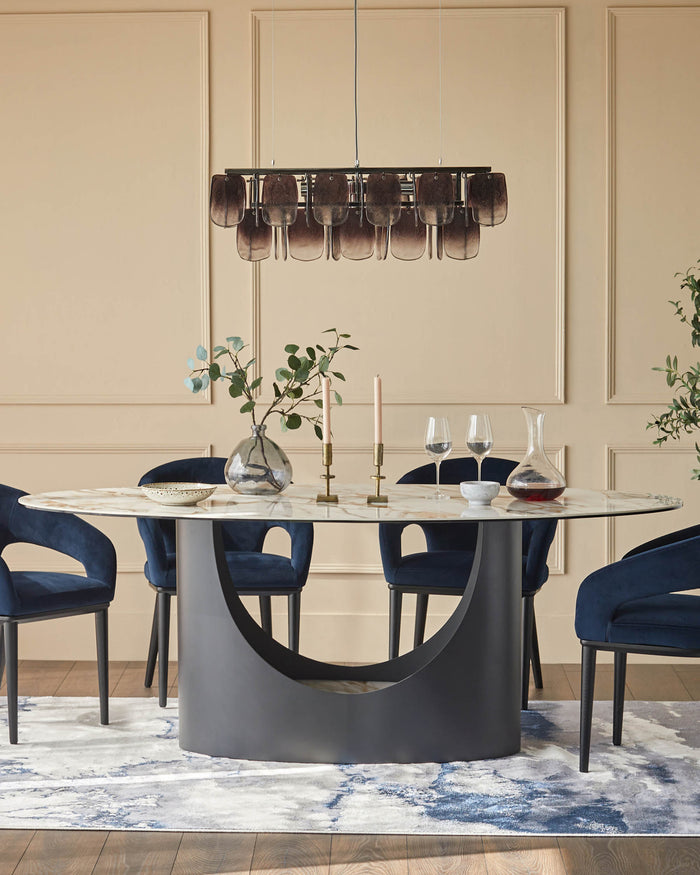 A stylish dining set with blue velvet chairs, a marble-topped table and a modern chandelier over a patterned rug.