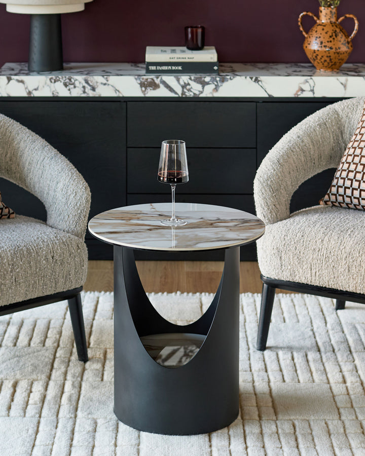 Giotto side table in natural ceramic with round marble-effect top and cylindrical black base, styled in modern living room setting.