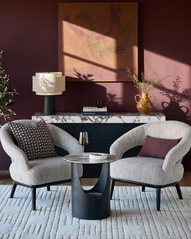 Giotto side table in ceramic natural finish, pedestal base design, styled in modern living room setting.