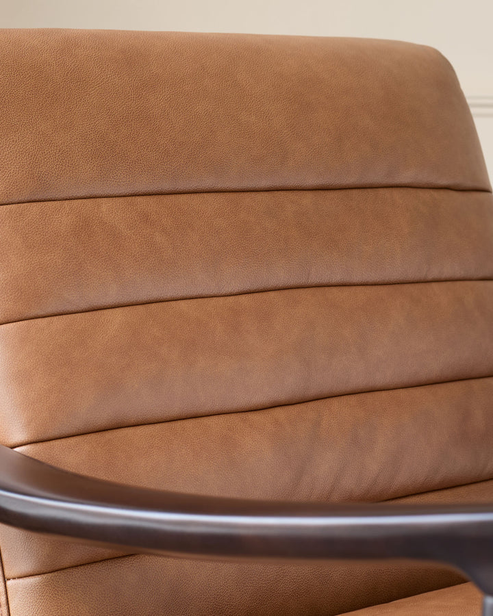 Greyson tan leather accent chair, close-up of padded seat cushions and curved armrest detail.