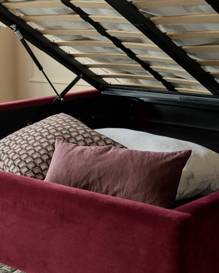Grove King Ottoman Bed in rose velvet with open storage, displaying plum pillows and patterned bedding with skylight above.
