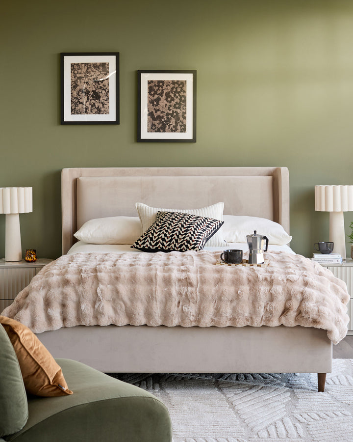 Grove King Ottoman Bed in champagne velvet, upholstered headboard with wing details, styled in bedroom setting.