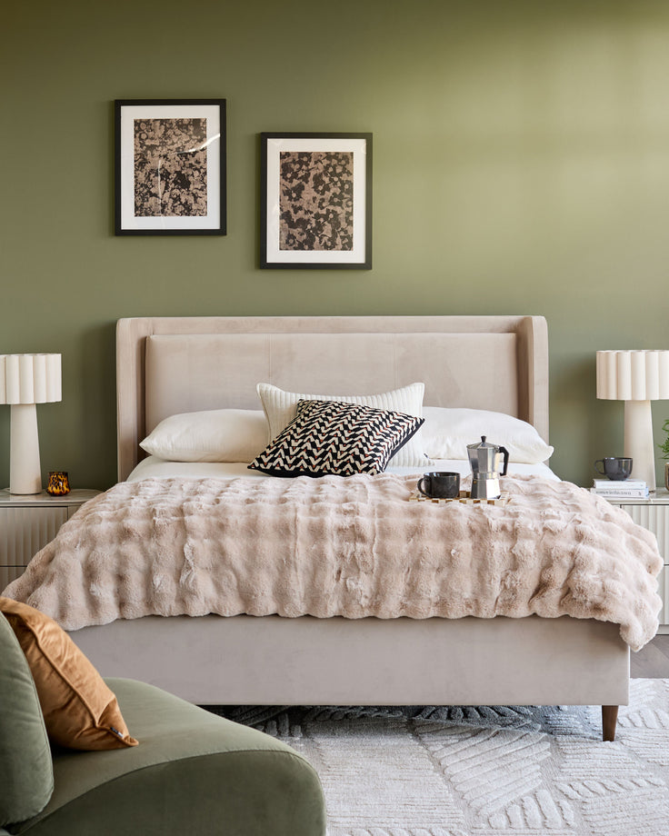Grove King Ottoman Bed in champagne velvet, upholstered headboard with wing details, styled in bedroom setting.