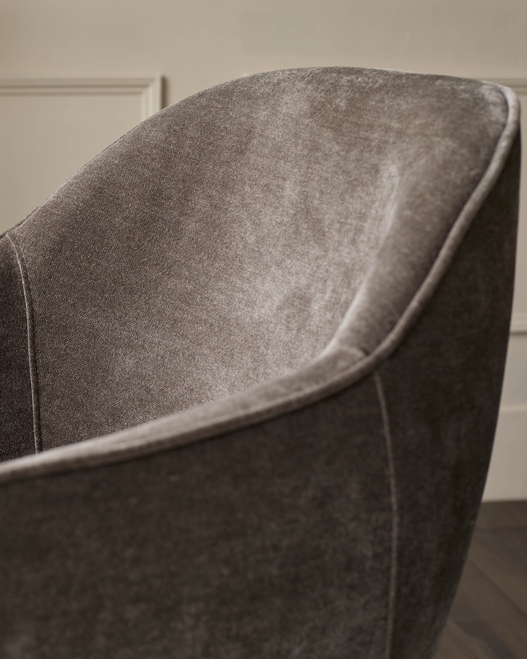 Close-up of a stylish upholstered chair in a neutral shade, showcasing its textured fabric and modern design.