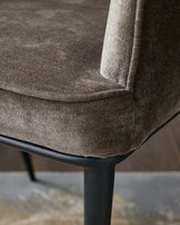 Close up of a brown upholstered chair with dark legs. The chair is stylish and modern, perfect for any home.
