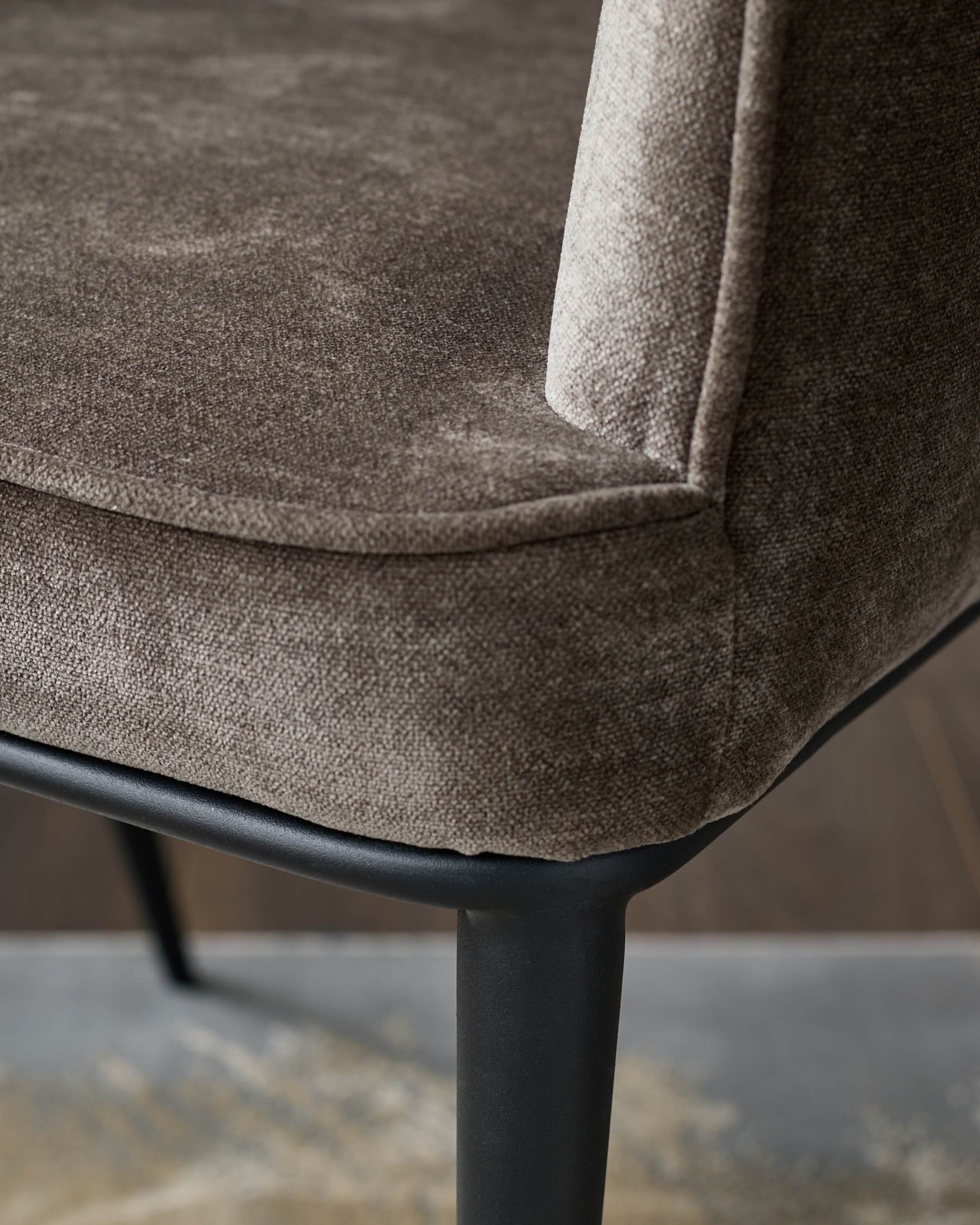 Close up of a brown upholstered chair with dark legs. The chair is stylish and modern, perfect for any home.