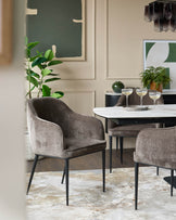 Dining area with upholstered chairs and a modern table. Neutral tones with pops of green.