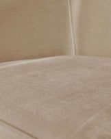Close-up of a cream-coloured fabric sofa, focus on the texture of the seat and the clean lines of the back.