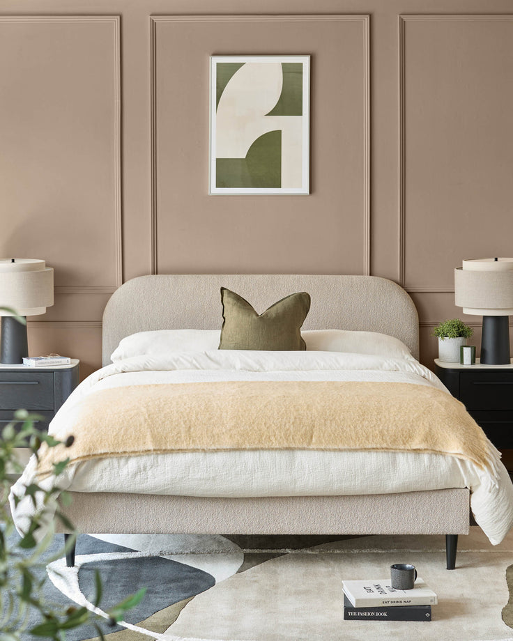 Bedroom featuring a neutral bed with side tables, lamps, and a framed print above the bed.