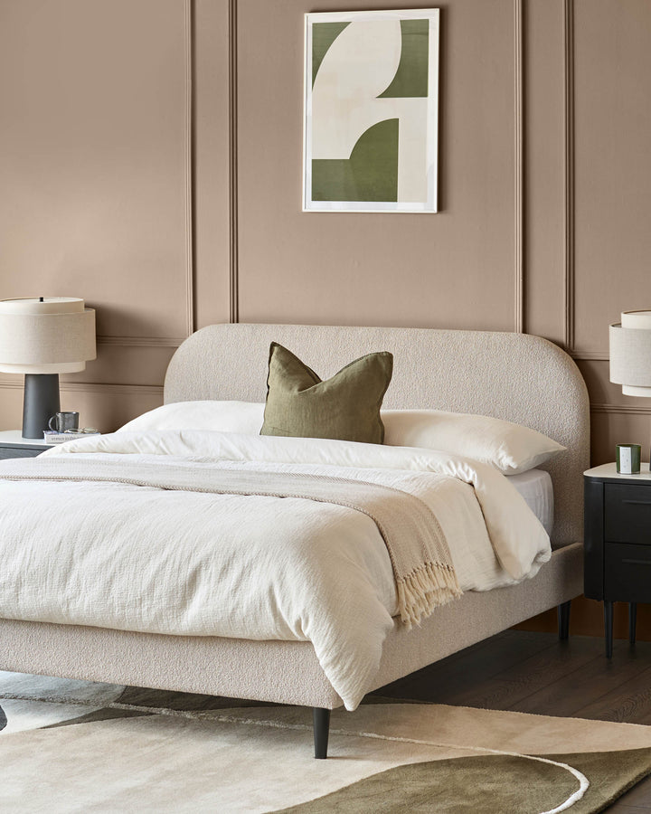 A modern bedroom featuring a boucle bed, bedside tables, lamps, and a geometric rug, styled in neutral and olive tones.
