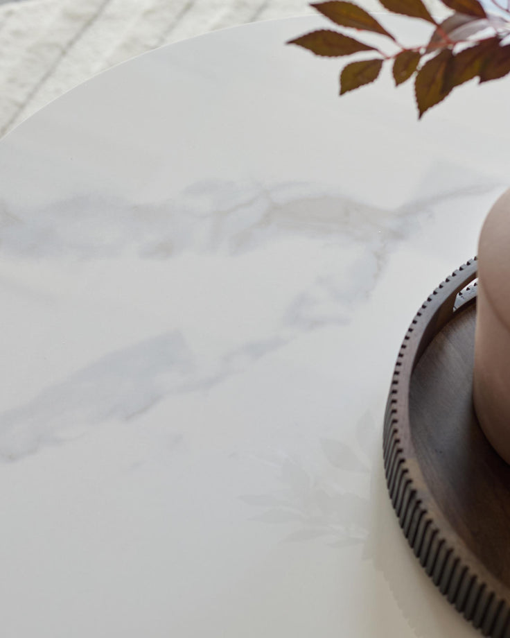 Close up of a marble-topped table with a wooden tray and foliage. A contemporary and stylish piece.