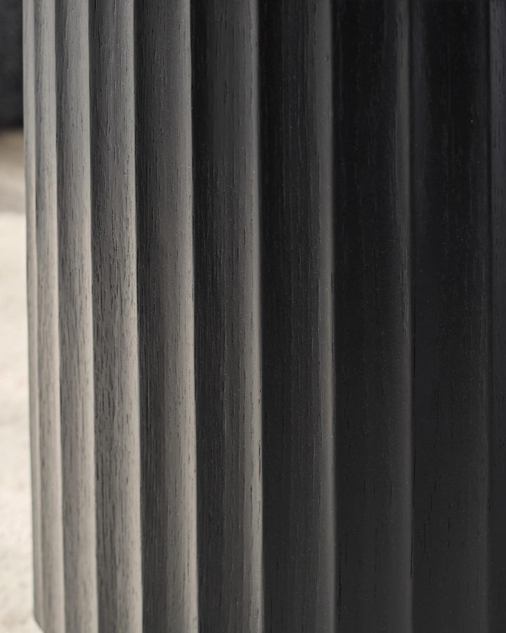 Close up of a dark wood table with vertical ridges. Striking texture and minimalist design for a modern home.
