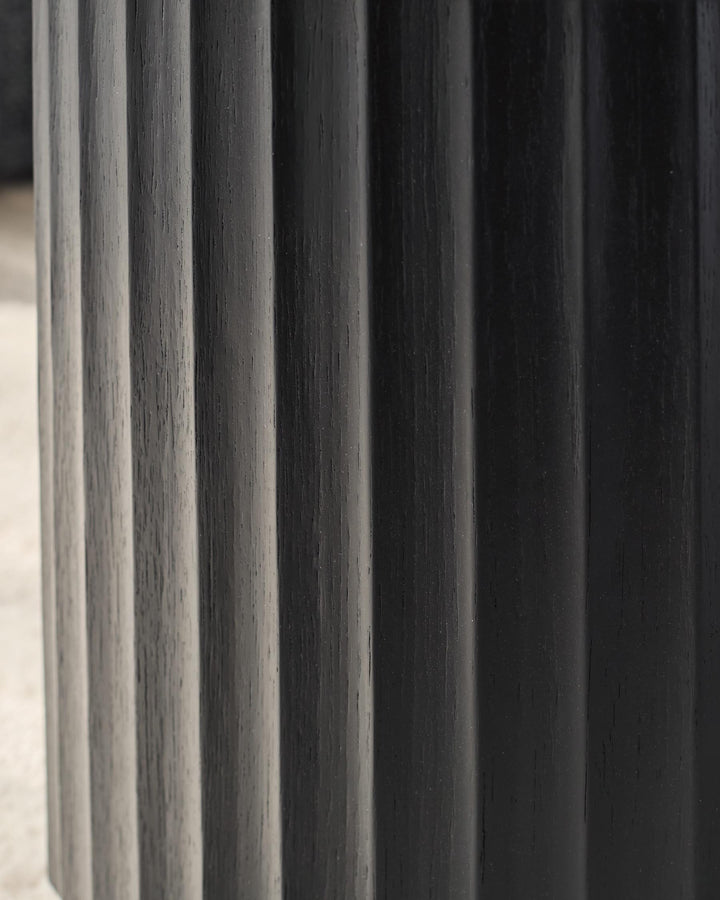 Close-up of dark wood furniture with a vertically grooved, textured design. Modern and stylish furniture detail.