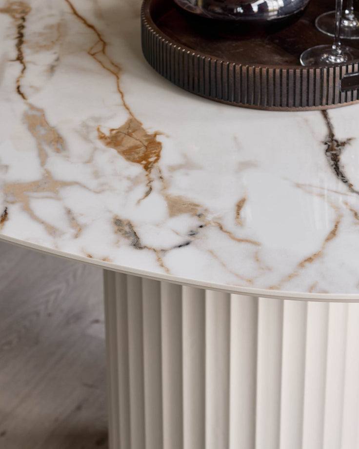 Close-up of a marble-effect table with a fluted base and a ridged tray with glasses on top.