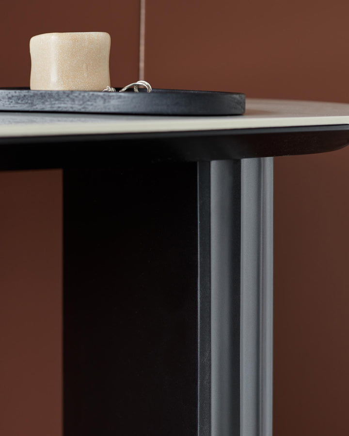 A modern side table with a sleek black frame, pale stone top and decorative accessories on a dark tray.
