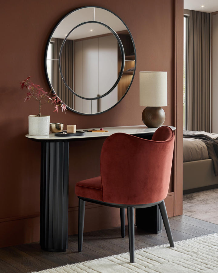 Dressing table with round mirror and rust coloured velvet chair. Modern furniture design for the bedroom.