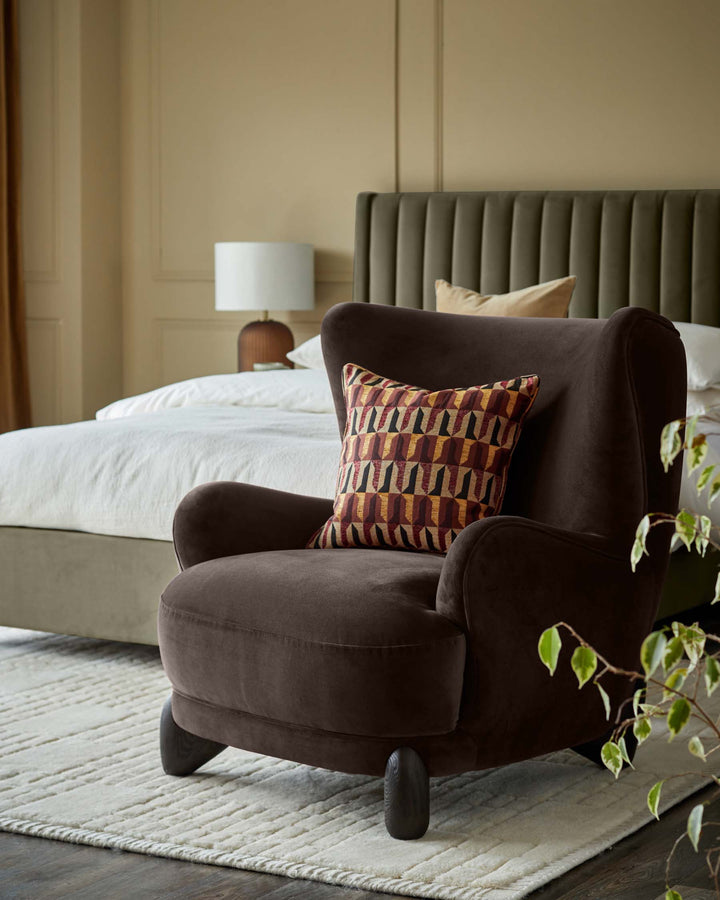 A brown wingback chair with patterned cushion sits on a textured rug in a bedroom setting.