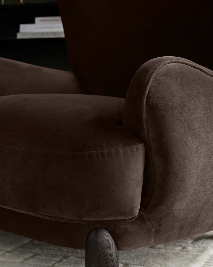 Close-up of a brown velvet armchair, showcasing its plush texture and elegant design.