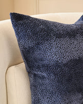 Navy textured cushion with boucle weave displayed on a cream upholstered armchair.