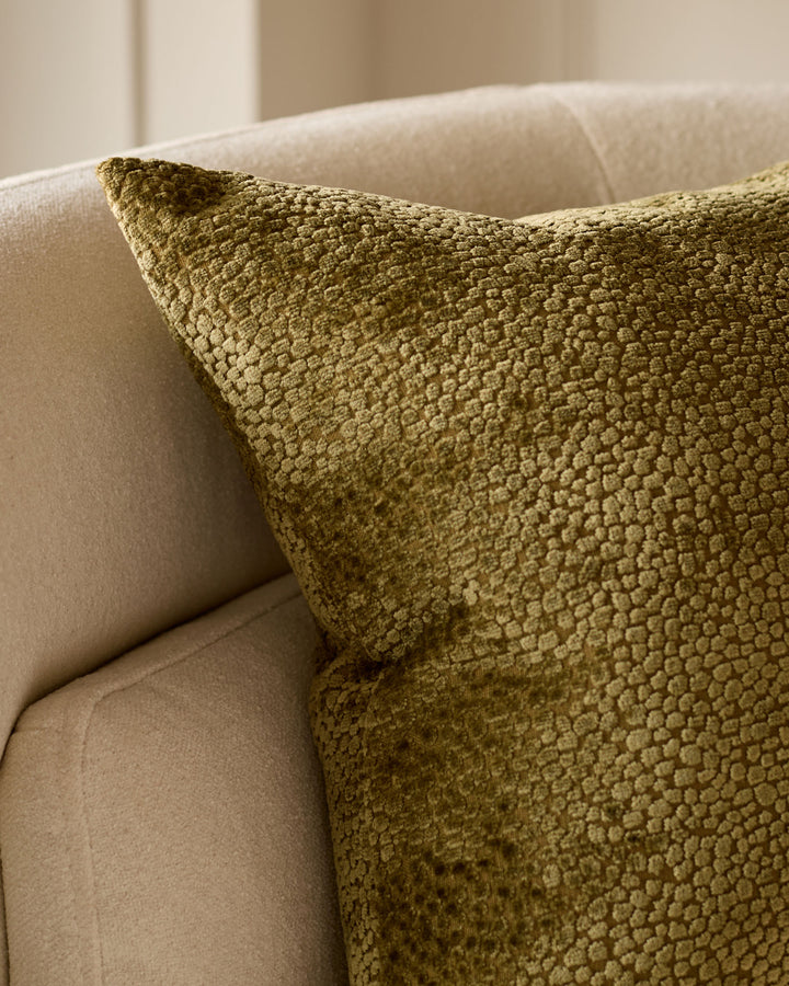 Harlene medium cushion in olive green with textured weave, displayed on a cream sofa.