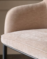 Harley bar stool in champagne fabric, close-up of curved backrest and seat with dark metal base.