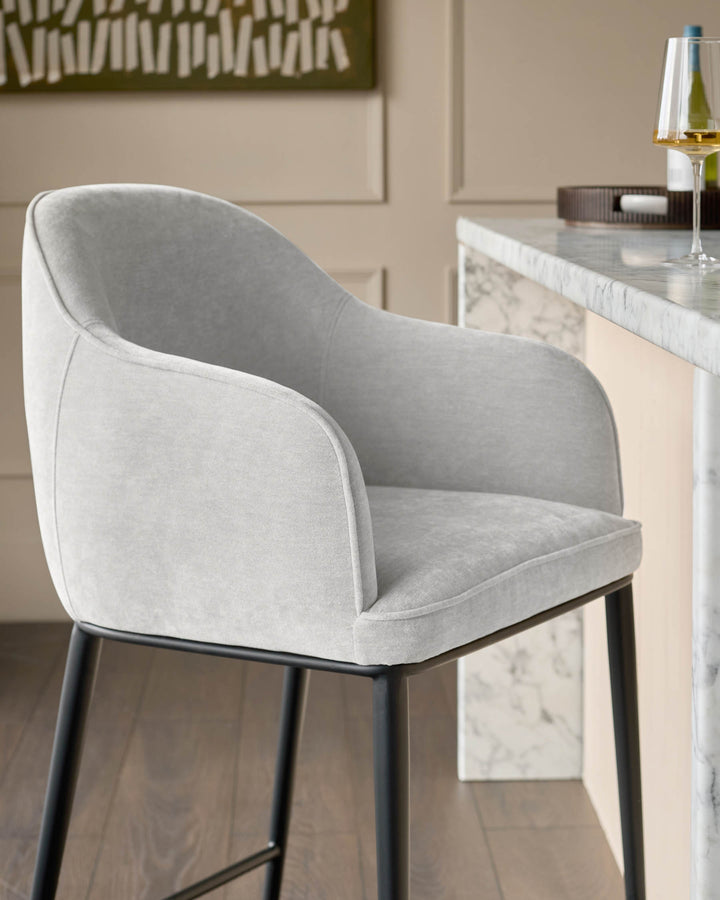 Harley bar stool in natural grey fabric with curved backrest and black metal legs, positioned at marble counter.