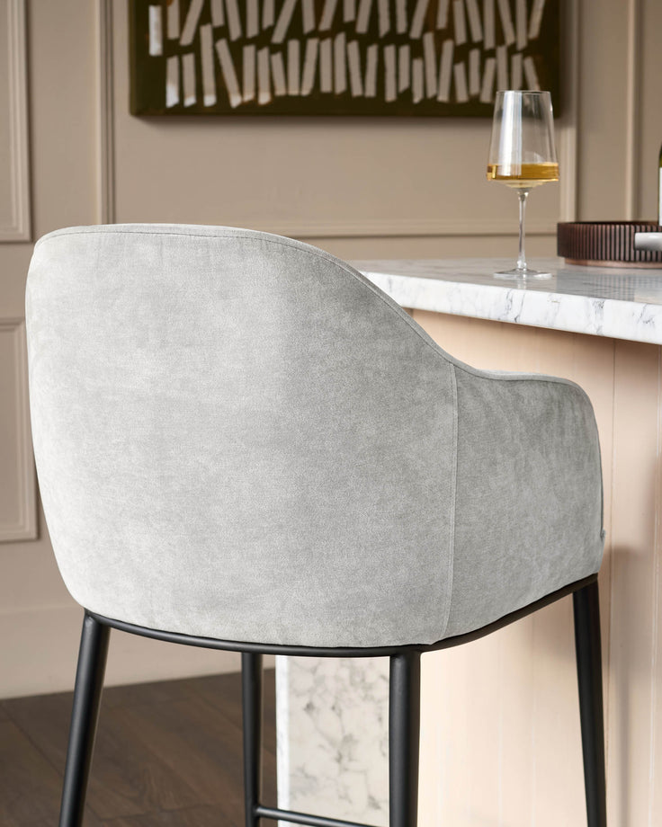 Harley bar stool in natural grey fabric, rear view showing curved backrest and black legs at marble counter.